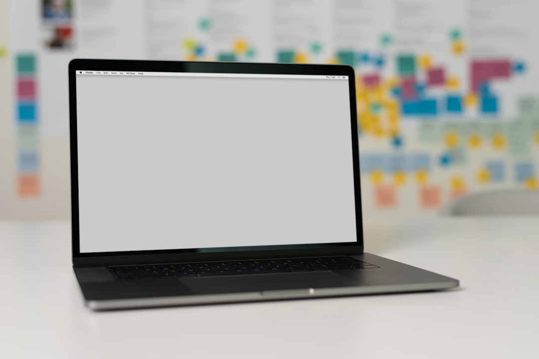 A blank laptop screen on a table with colorful sticky notes in the background.