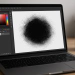 A laptop displaying a black halftone dot pattern on the screen, with a coffee mug and plant in the background.